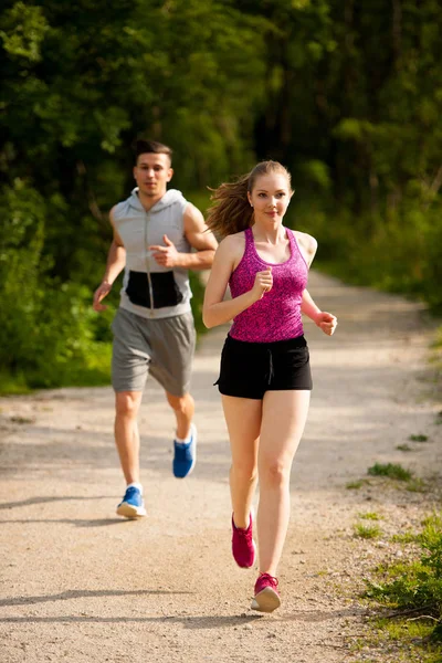 Pareja joven y activa corriendo en el parque — Foto de Stock