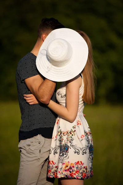 Άνδρας και γυναίκα φιλιά κρύβονται πίσω από το καλοκαιρινό καπέλο — Φωτογραφία Αρχείου