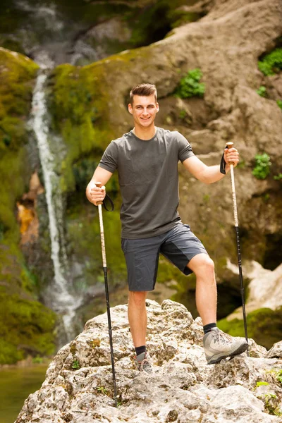 Activo joven senderismo en las montañas cerca de la cascada en un arroyo —  Fotos de Stock