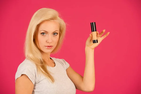 Beautiful young blonde woman holds powder foundation bottle — Stock Photo, Image