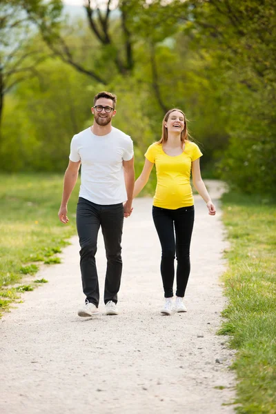 Pregnant woman with her man - happy couple in park — Stock Photo, Image