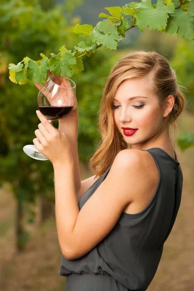 Attraktive stilvolle Frau trinkt ein Glas Rotwein im Weinberg — Stockfoto
