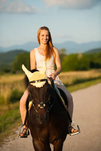 Giovane donna attiva cavalcare un cavallo nella natura — Foto Stock