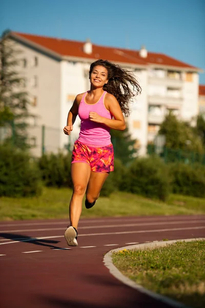 Aktive junge Frau läuft am Sommernachmittag auf Leichtathletik-Bahn — Stockfoto