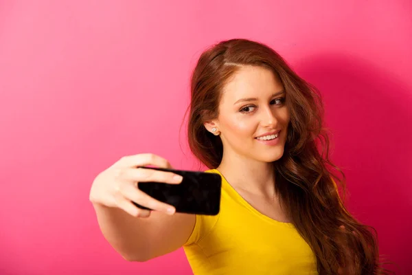 Donna scattare foto selfie su vibrante sfondo rosa — Foto Stock