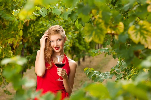 Attraktive stilvolle Frau trinkt ein Glas Rotwein im Weinberg — Stockfoto