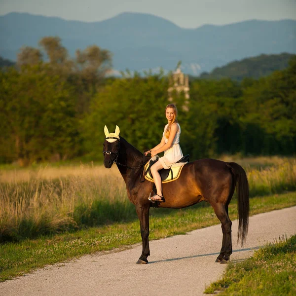 Giovane donna attiva cavalcare un cavallo nella natura — Foto Stock