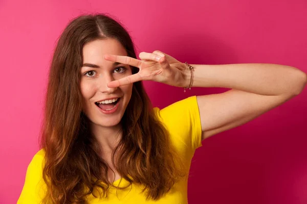 Atraktivní mladá žena v žluté tričko přes živé růžové pozadí — Stock fotografie
