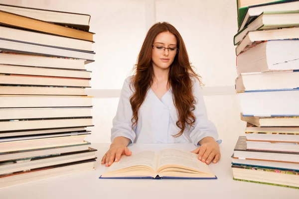 Приваблива молода жінка вивчає купа книг на своєму столі — стокове фото