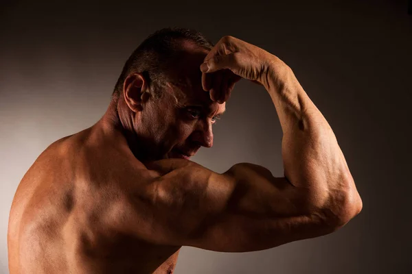 Bodybuilder pose en studio sur fond sombre — Photo