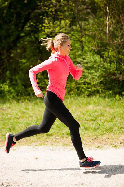 Jovem mulher de vestido rosa e preto corre cross country em um quente — Fotografia de Stock