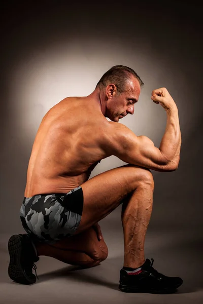 Bodybuilder pose en studio sur fond sombre — Photo