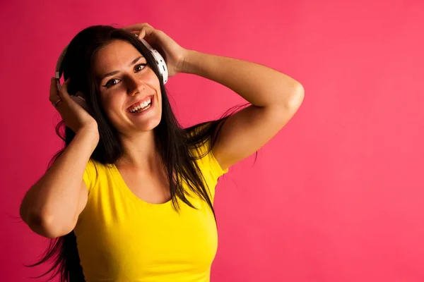 Atrakcyjna młoda kobieta słucha muzyki na różowym tle — Zdjęcie stockowe