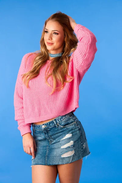 Όμορφη νεαρή γυναίκα σε τζιν φούστα και ροζ πουλόβερ — Φωτογραφία Αρχείου