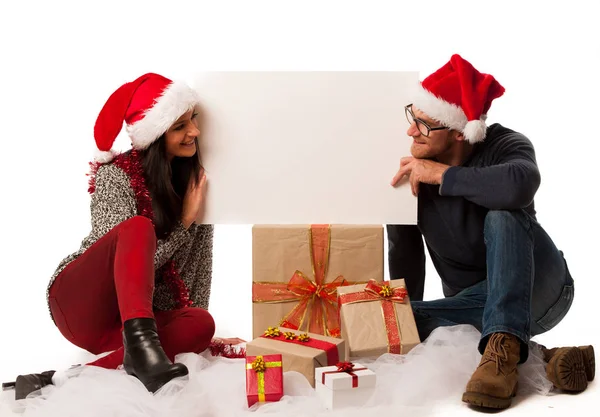 Young couple in santa hat holding blank board for advertisement, — Stock Photo, Image