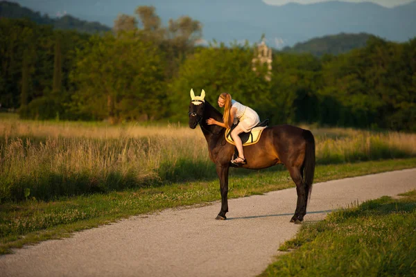 Giovane donna attiva cavalcare un cavallo nella natura — Foto Stock