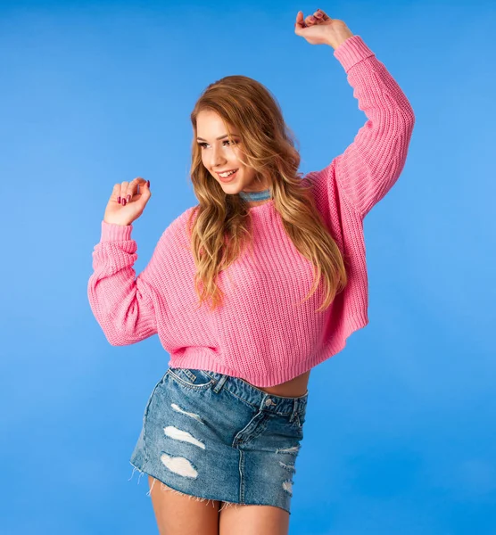 Mulher bonita em suéter rosa e saia jeans sobre fundo azul — Fotografia de Stock