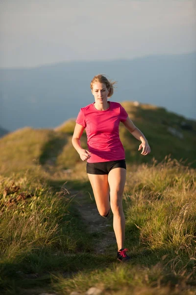 Mulher corre em um topo das montanhas com cordilheira nas costas — Fotografia de Stock