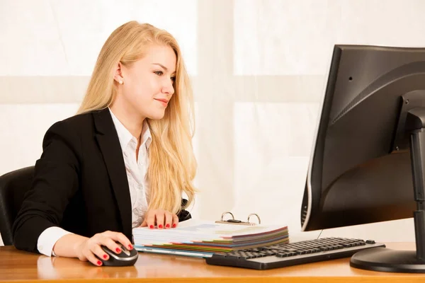 Beautiful young blonde woman working on computer in her office — Stock Photo, Image