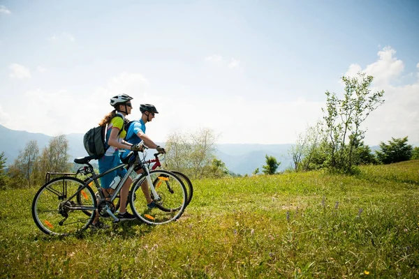 ACTIVE Young couple biking on a forest road in mountain on a spr — Stock Photo, Image