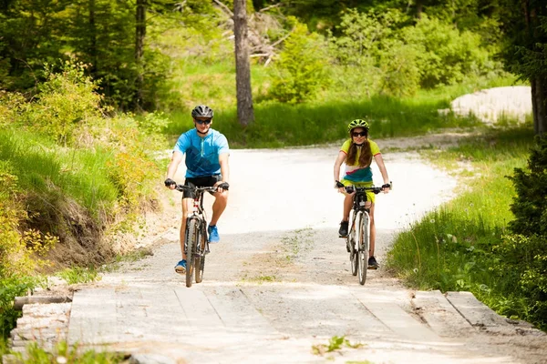 ACTIVE Young couple biking on a forest road in mountain on a spr — Stock Photo, Image