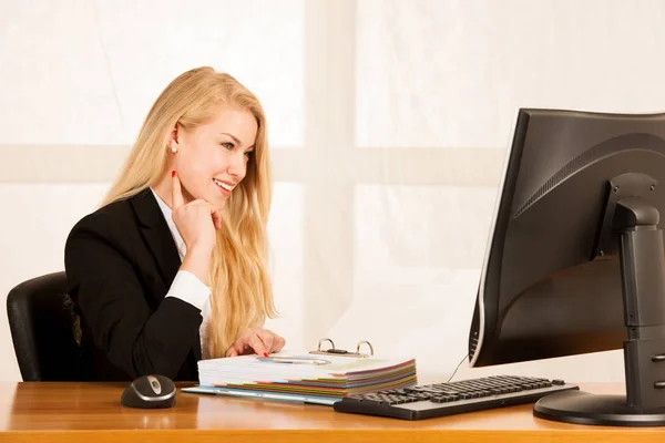 Beautiful young blonde woman working on computer in her office — Stock Photo, Image