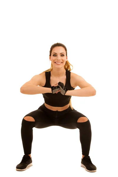 Jonge sportieve vrouw doen squats geïsoleerd op witte achtergrond — Stockfoto