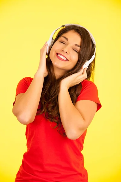 Bela jovem mulher no vermelho t-shirt ouvir música sobre amarelo ba — Fotografia de Stock