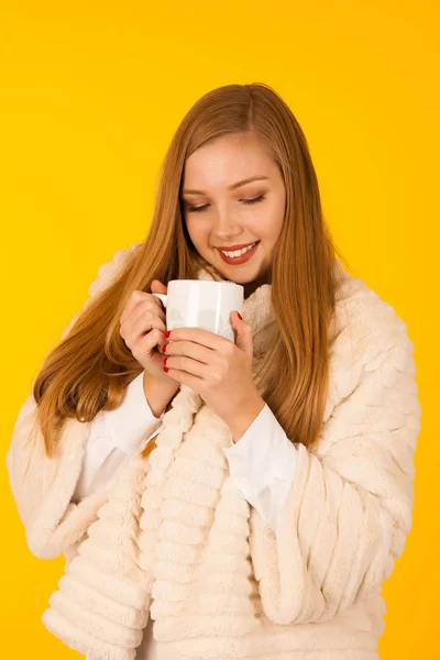 Piękna kobieta w futra kurtki zimowe napoje herbata nad żółty ba — Zdjęcie stockowe