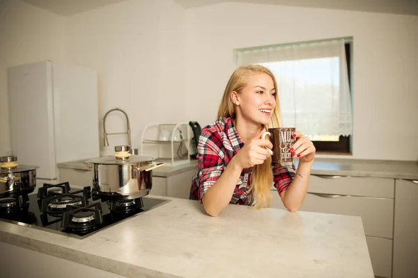 Beautiful young woman drinks coffee in the kitchen — Stock Photo, Image