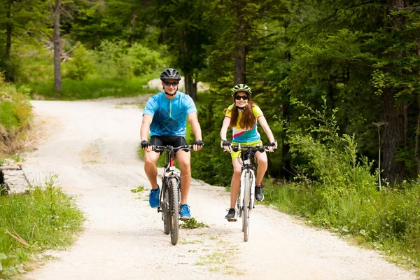 ACTIVE Young couple biking on a forest road in mountain on a spr — Stock Photo, Image