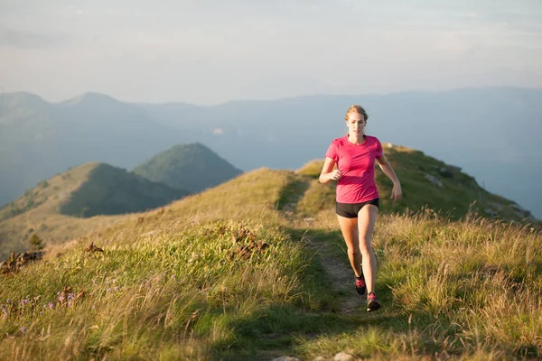 Mulher corre em um topo das montanhas com cordilheira nas costas — Fotografia de Stock