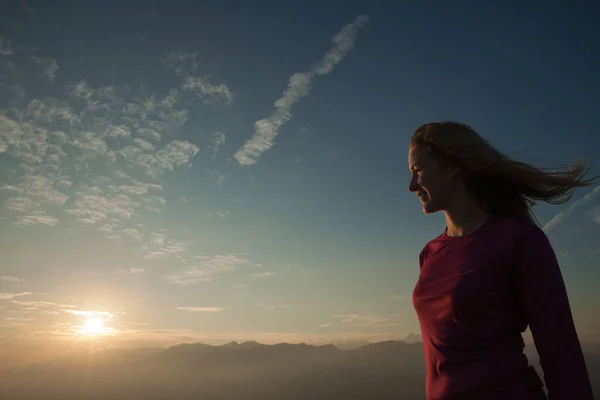 Woamn se dresse sur un sommet de montagne au coucher du soleil — Photo