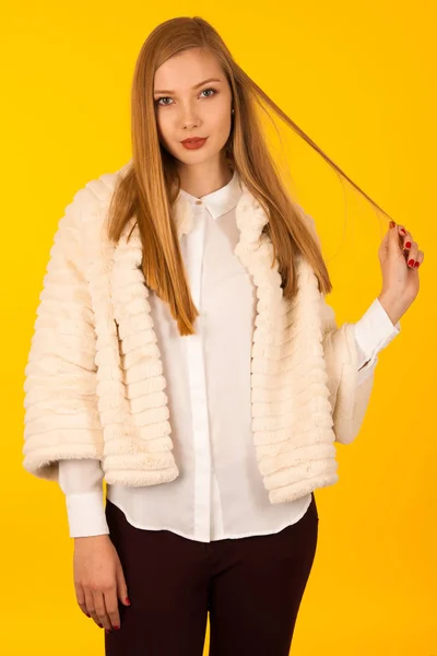 Portret van de schoonheid van de vrouw in bont winter jas over gele backgr — Stockfoto