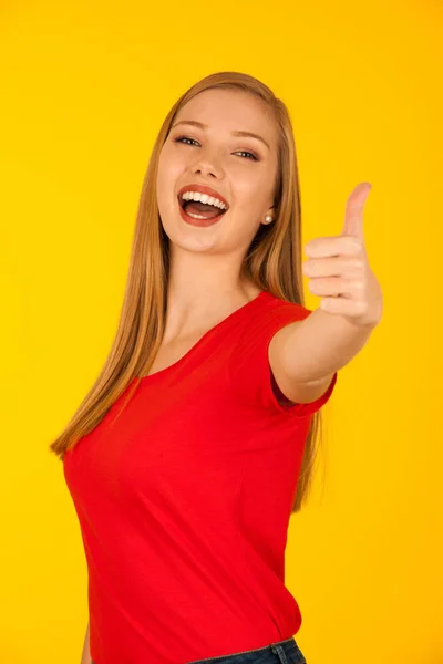 美丽的年轻女子在红色 T恤超过黄色背景显示拇指作为成功的手势 — 图库照片