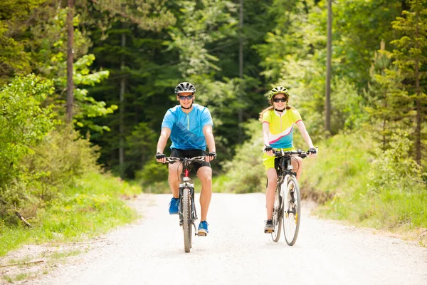 ACTIVE Young couple biking on a forest road in mountain on a spr — Stock Photo, Image