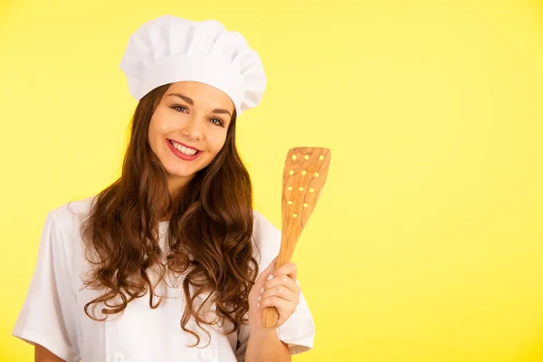 Beautiful chef - cute brunette woman in cook uniform over yellow — Stock Photo, Image