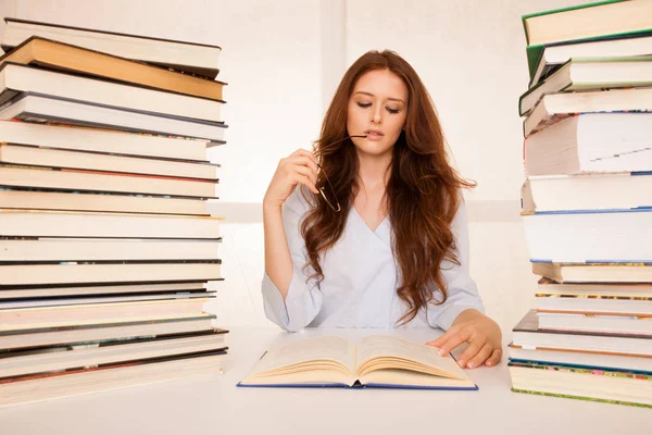 Vonzó fiatal nő tanulmányok hugr könyv cölöpök az asztalára — Stock Fotó