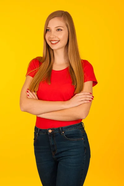 Beautiful young woma in red t shirt and jeans over yellow backgr — Stock Photo, Image