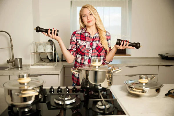 Beautiful young woman in kitchen cooks a delicious meal uncertai — Stock Photo, Image