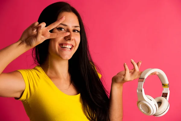 Attractive young woman listens music over pink background — Stock Photo, Image