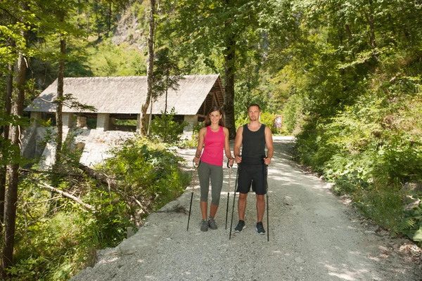 Casal jovem ativo em uma caminhada na floresta em um dia de wummer quente — Fotografia de Stock