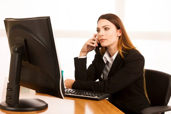 Angry business woman talks on smert phone in office at her desk — Stock Photo, Image