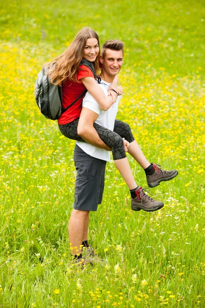 Aktiva lekfulla coupel vandring på en äng i ratly vårgrön g — Stockfoto