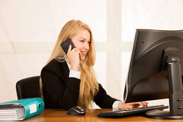 Beautiful business woman talks on a smart phone in her office at — Stock Photo, Image