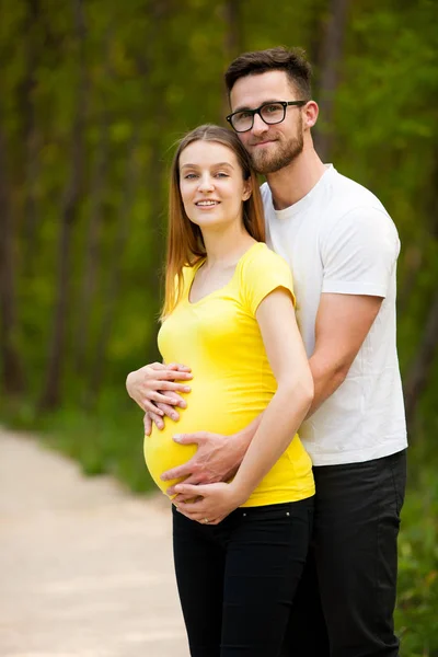 Gravid kvinna med sin man - lyckliga paret i park — Stockfoto