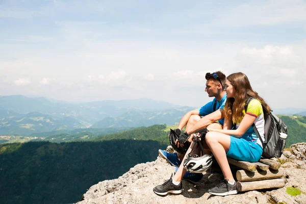 Casal ativo descansa depois de andar de bicicleta em um topo de montanha — Fotografia de Stock