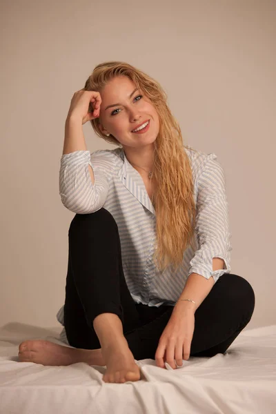 Vacker ung blond kvinna stting på sängen — Stockfoto