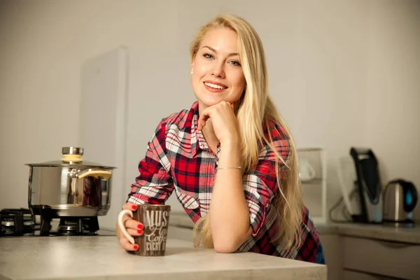 Mooie jonge vrouw drinkt koffie in de keuken — Stockfoto