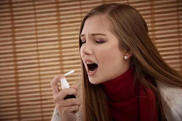 Spray for sore throat. Photo of a woman who treats her throat with a spray and sprinkles it in her mouth. The concept of health and disease